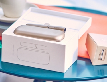 A package containing a gold IQOS device and holder.
