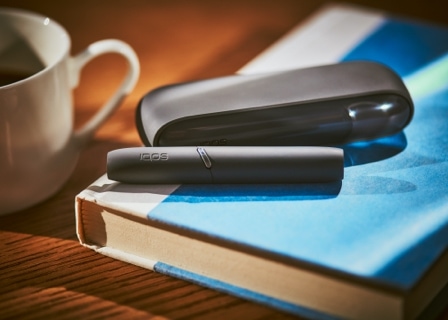 Black IQOS 3 DUO holder and charger on a book