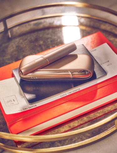 A gold IQOS DUO device on an orange copybook