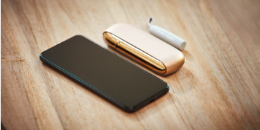 A mobile and a gold IQOS on a table