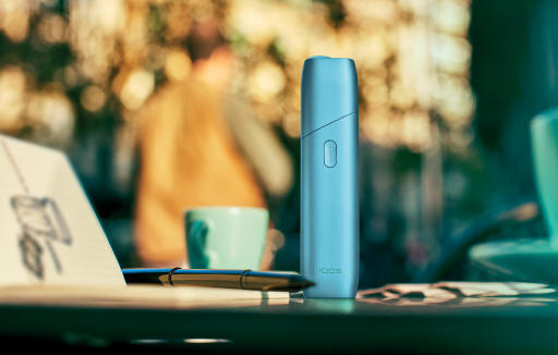 IQOS ORIGINALS ONE on a coffee table, in turquoise color.